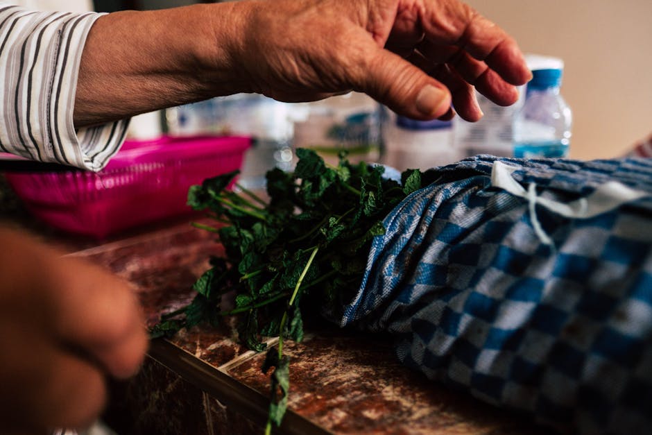 Detailed shot of hands arranging fresh mint leaves on a table indoors, capturing a rustic kitchen scene.