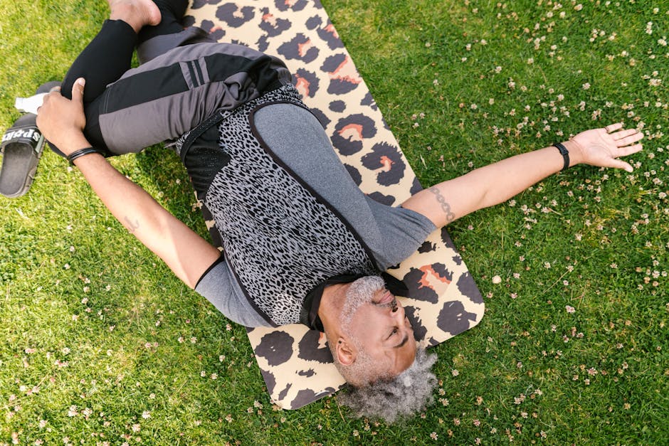 Senior man doing yoga stretches on a patterned mat outdoors, promoting wellness and flexibility.