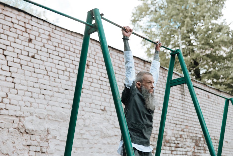 Bearded man exercising by hanging on monkey bars outdoors in a playground area.