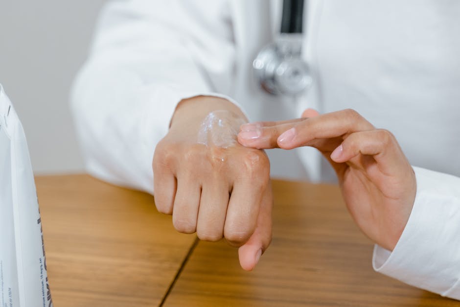 Close-up of a doctor applying lotion on their hand, focusing on skincare.