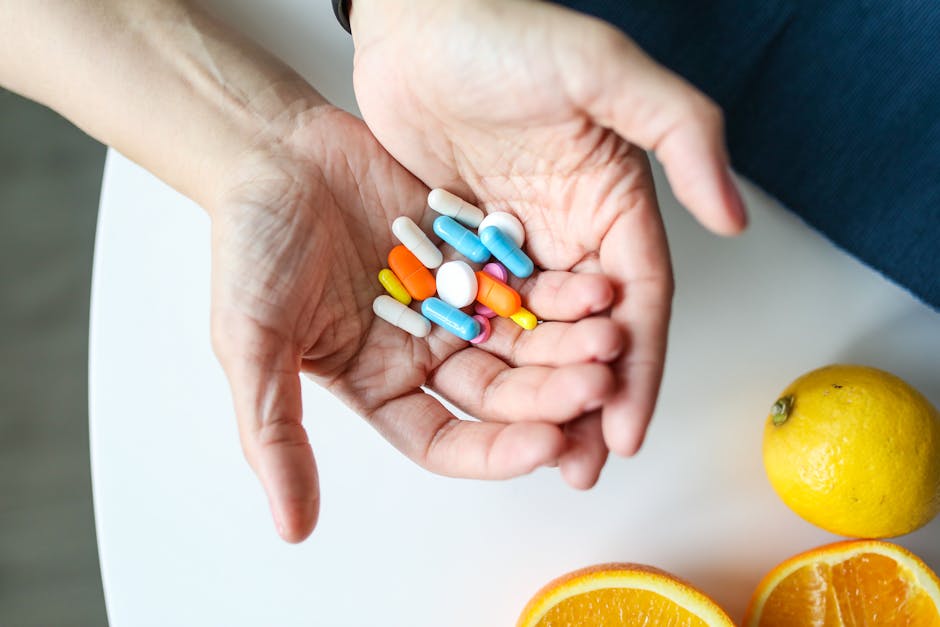 Close-up of hands holding multicolored pills with oranges, symbolizing health and nutrition.