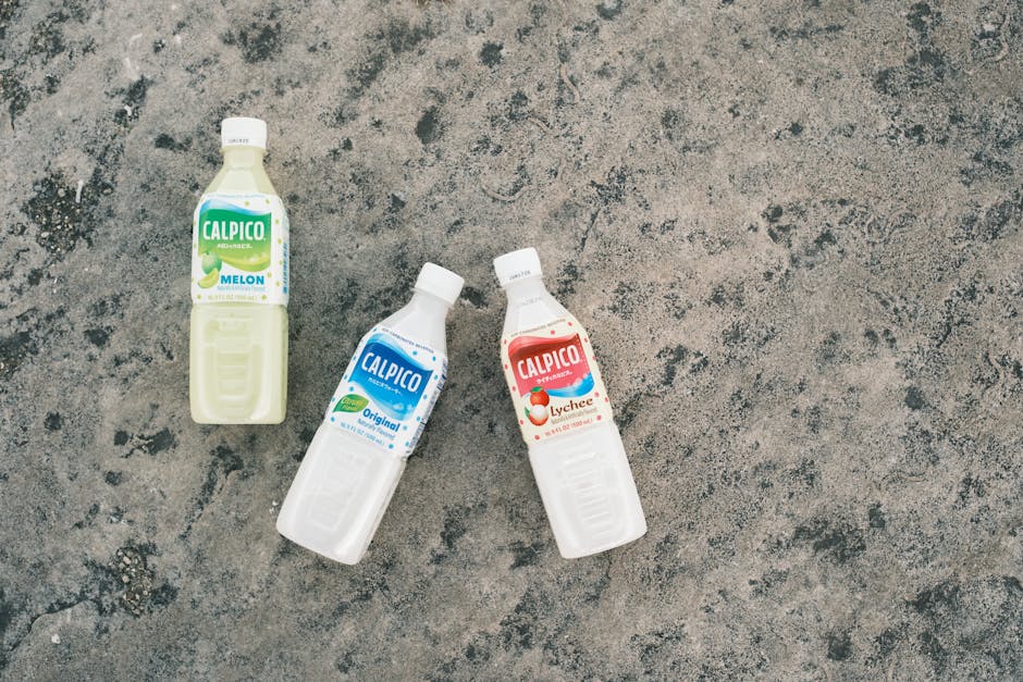 Three Calpico drink bottles in different flavors on a textured concrete background.
