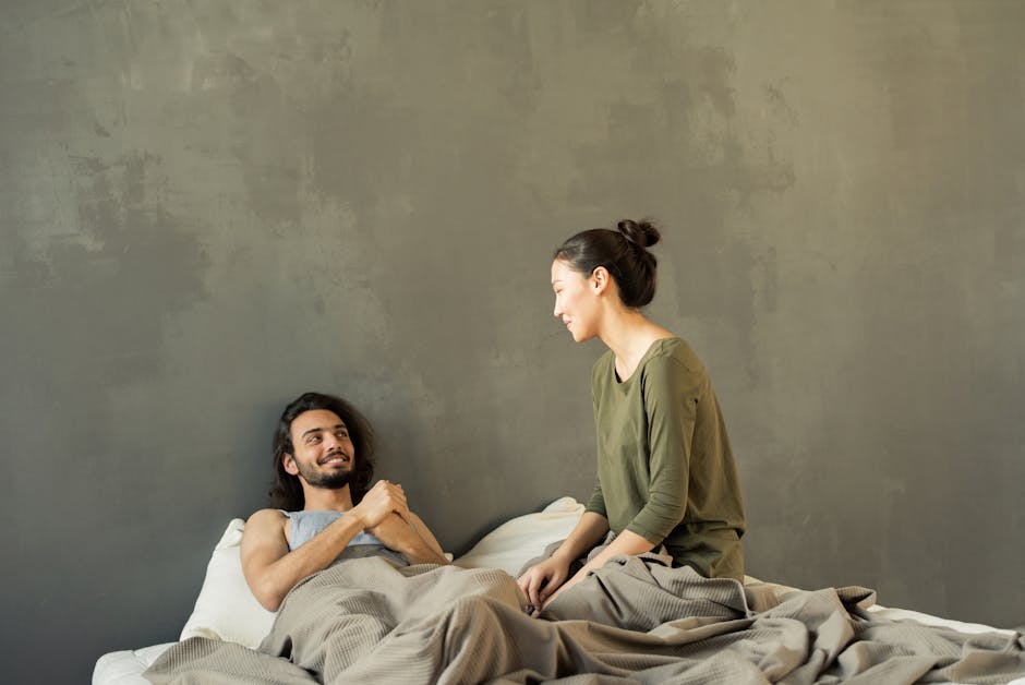 A happy couple enjoys a relaxing moment indoors, sitting on a cozy bed, symbolizing love and togetherness.