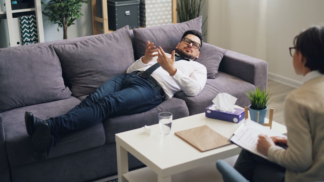 a man laying on a couch talking on a cell phone