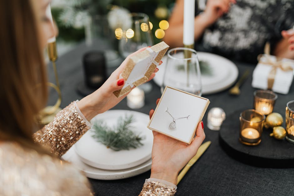 Woman opening a necklace gift box at a beautifully set holiday dinner table.