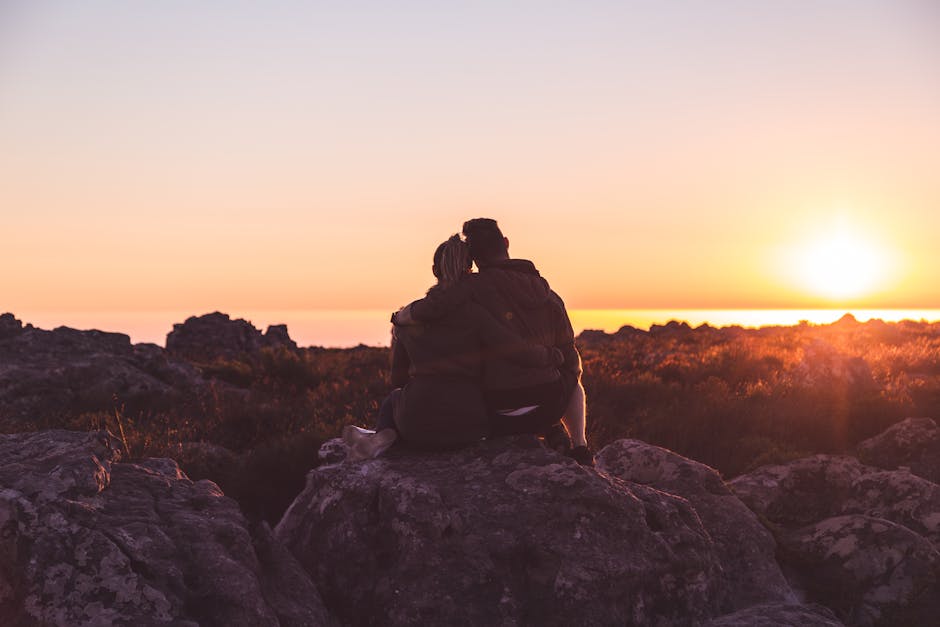 A couple embraces on rocky terrain during a golden sunset in Cape Town.
