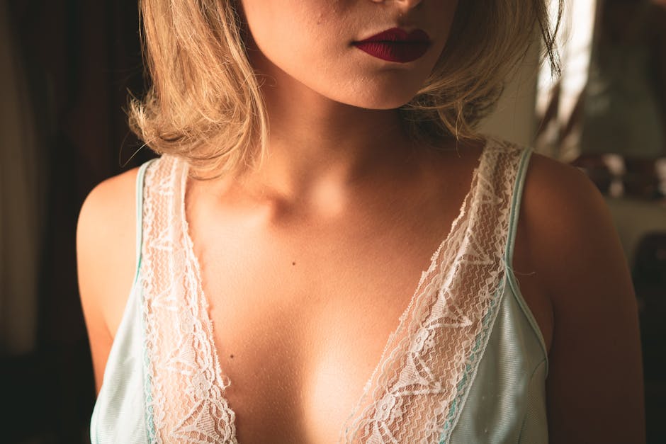 A close-up image of a woman wearing lace clothing, highlighting her red lips and soft skin.