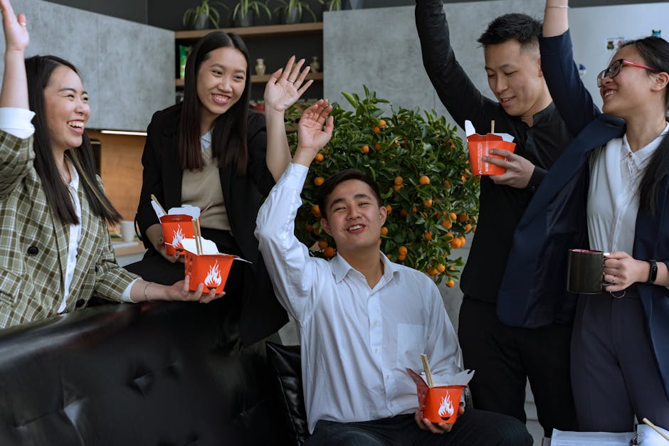 A group of coworkers celebrating with takeout noodles in a modern indoor setting.