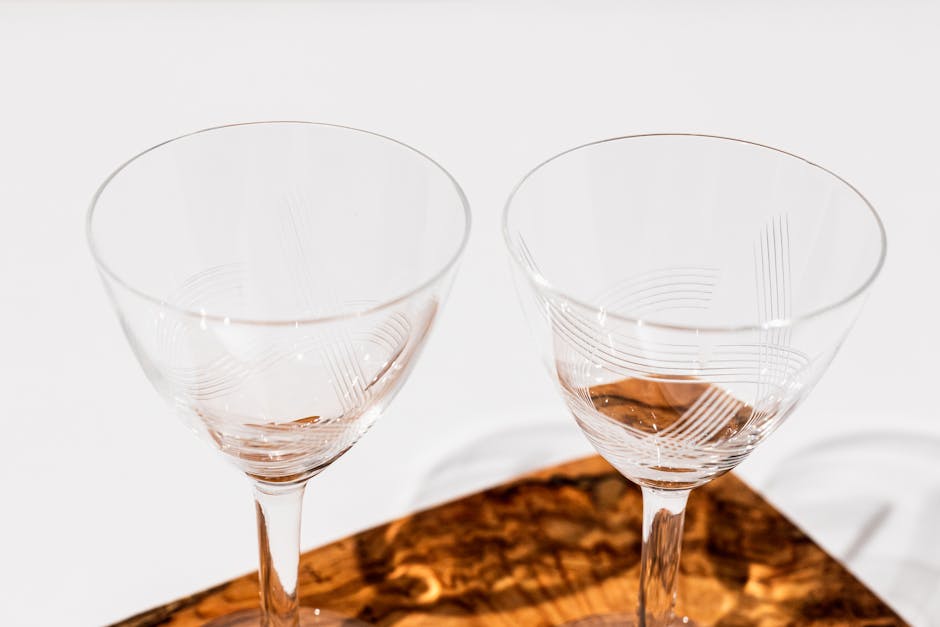 Two elegant crystal glasses placed on a textured wooden surface, capturing refined simplicity.