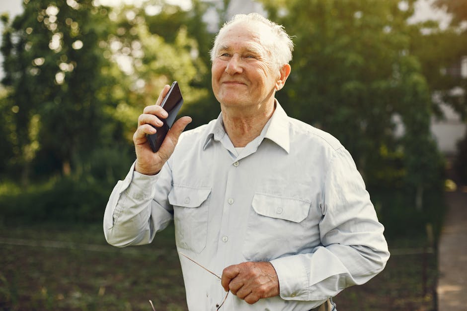 Smiling elderly man holding smartphone outdoors, basking in nature's tranquility.