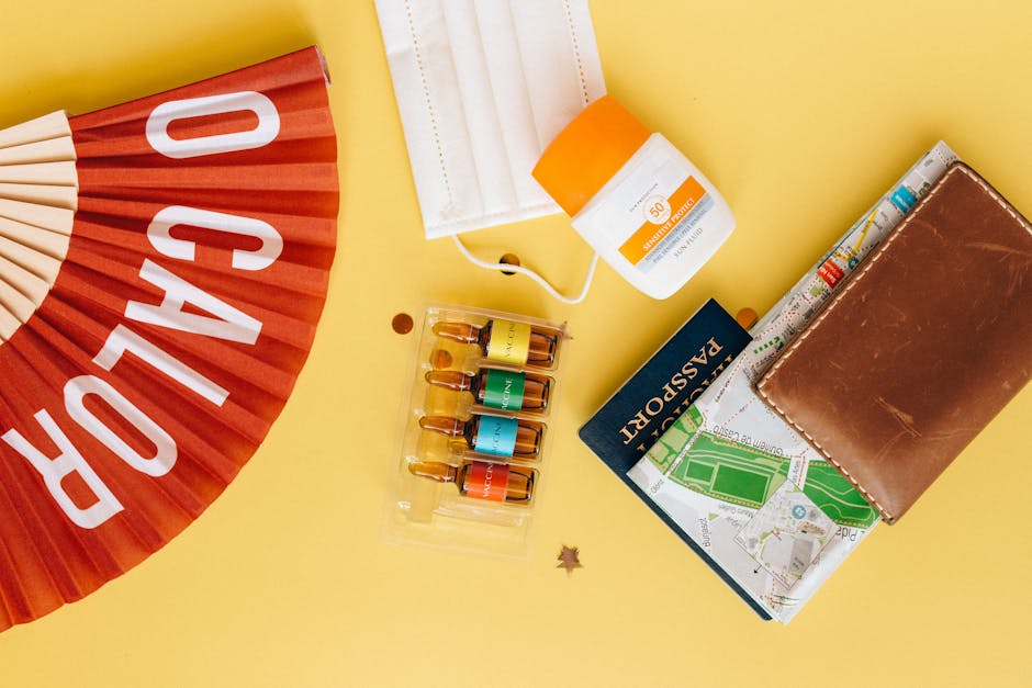 Flatlay of travel essentials like mask, vaccine, and sunscreen on yellow background.