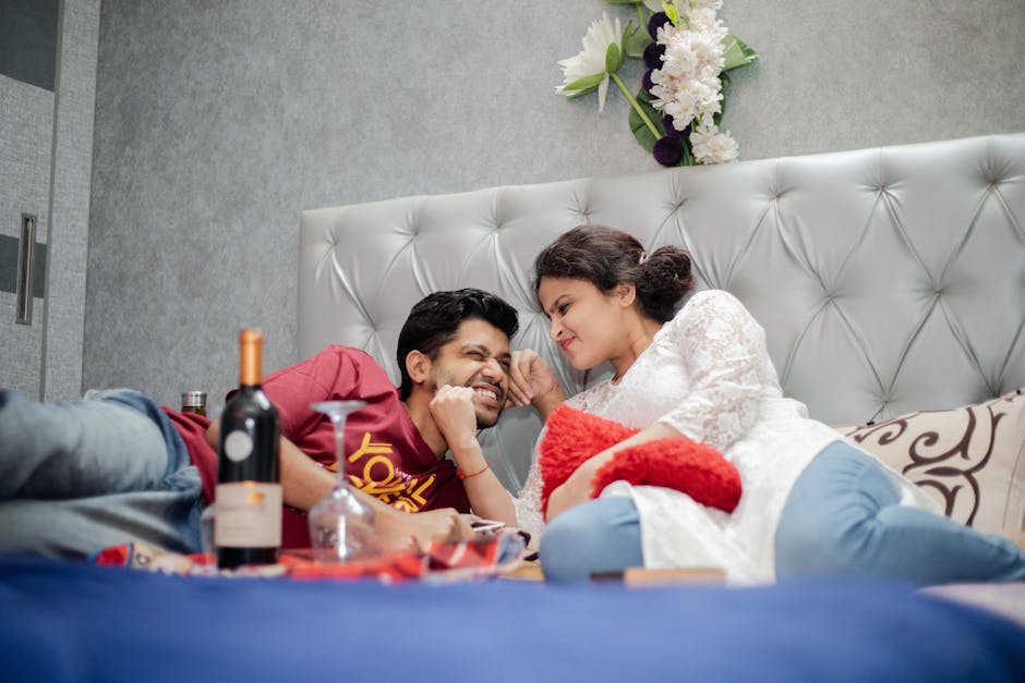 A happy couple enjoying a cozy date night indoors with wine and snacks, highlighting romance and relaxation.