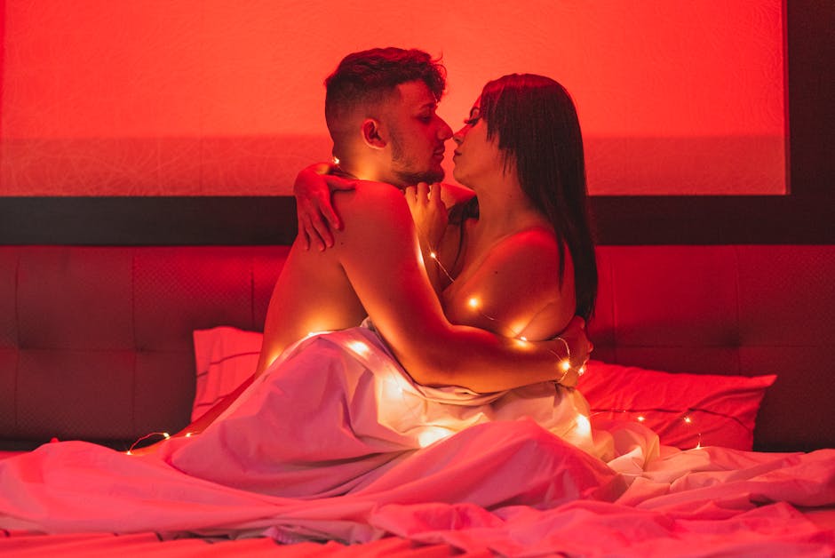 Passionate couple embracing under a warm red glow, wrapped in string lights for a cozy intimate atmosphere.