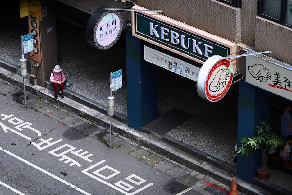Aerial view of a person waiting at a bus stop next to a store in Taipei, Taiwan.