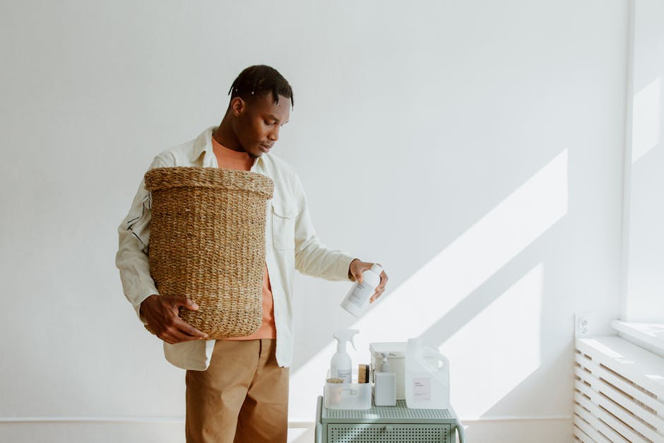 A man holds a laundry basket while selecting cleaning products, indoors
