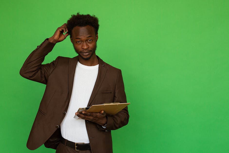 African American man scratching his head while holding a clipboard, studio shot.